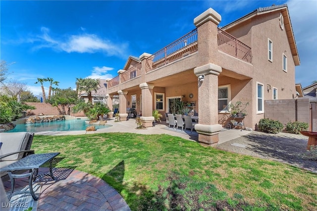 back of property featuring a patio, a balcony, fence, a yard, and stucco siding