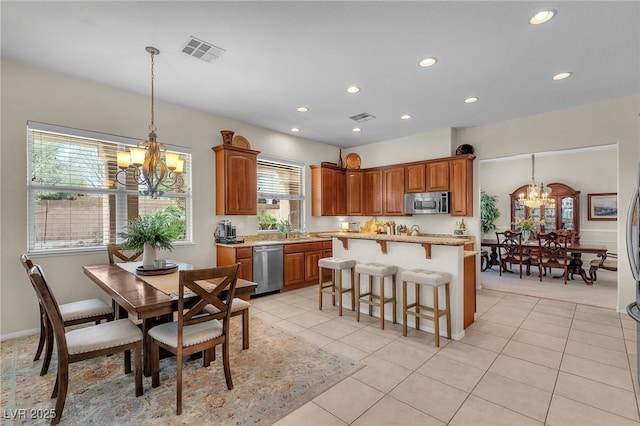 kitchen with appliances with stainless steel finishes, a chandelier, visible vents, and a kitchen breakfast bar