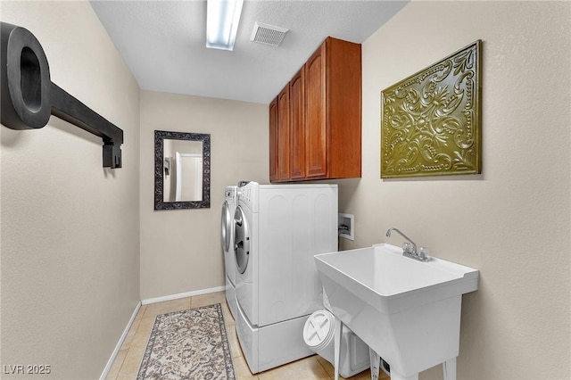 laundry room featuring washing machine and clothes dryer, cabinet space, visible vents, light tile patterned flooring, and a sink