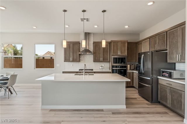 6312 Zephyr Ct, Las Vegas, NV 89149 - kitchen with wall chimney exhaust hood, stainless steel appliances, light countertops, tasteful backsplash, and a center island with sink