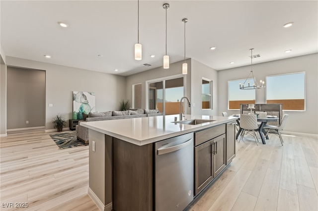 6312 Zephyr Ct, Las Vegas, NV 89149 - kitchen with stainless steel dishwasher, a sink, light countertops, light wood-style floors, and decorative light fixtures