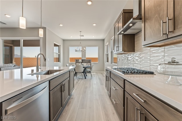 6312 Zephyr Ct, Las Vegas, NV 89149 - kitchen with appliances with stainless steel finishes, a sink, wall chimney range hood, light wood-type flooring, and light countertops