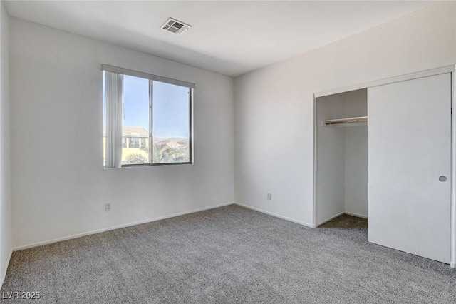 unfurnished bedroom featuring carpet floors, visible vents, and a closet