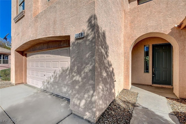 entrance to property featuring a garage and stucco siding