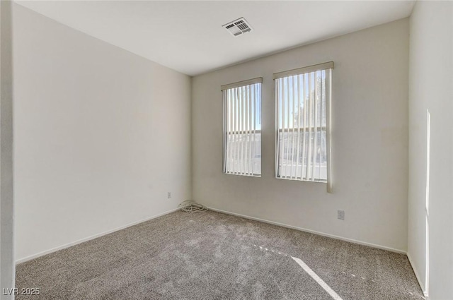 empty room featuring carpet, visible vents, and baseboards