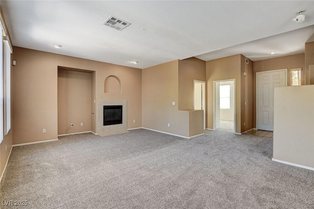 unfurnished living room with a fireplace, carpet flooring, visible vents, and baseboards