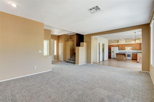 unfurnished living room featuring baseboards, stairway, visible vents, and light colored carpet