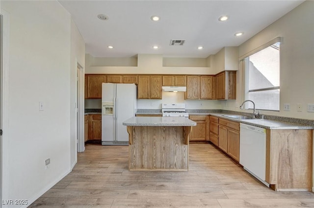 kitchen with a center island, visible vents, a sink, white appliances, and under cabinet range hood