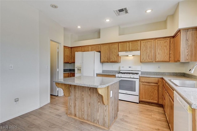 kitchen featuring white appliances, visible vents, light wood-type flooring, under cabinet range hood, and a sink