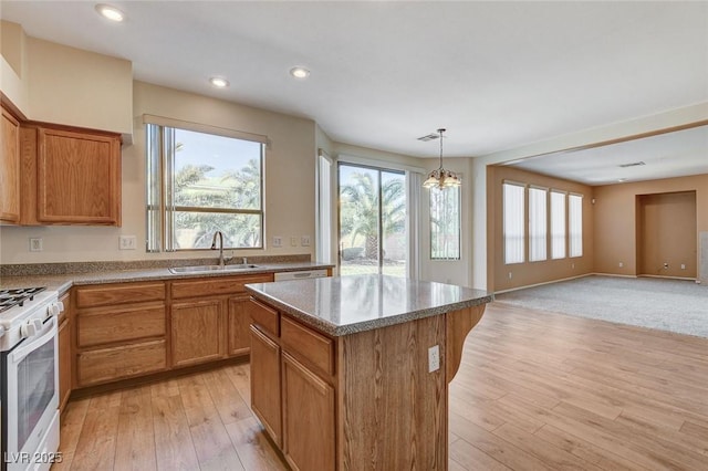 kitchen featuring plenty of natural light, white range with gas cooktop, a kitchen island, light wood-type flooring, and a sink