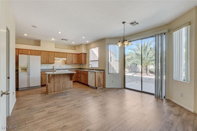 kitchen featuring light wood finished floors, white appliances, a sink, and visible vents