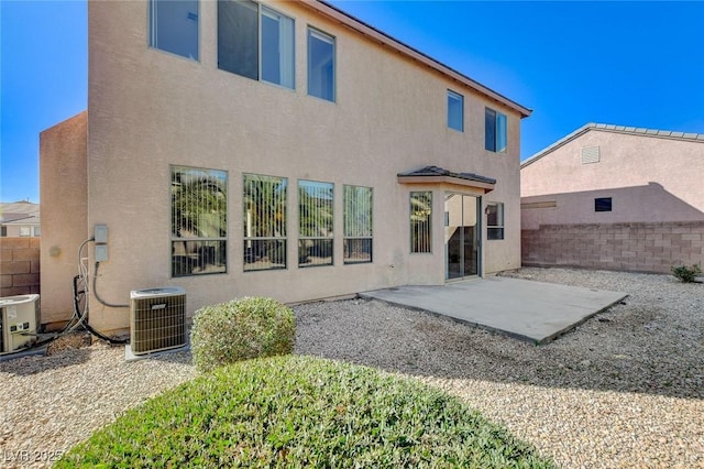 rear view of house featuring a patio, central AC unit, fence, and stucco siding