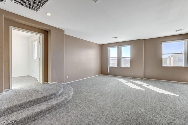 empty room featuring carpet, visible vents, and baseboards