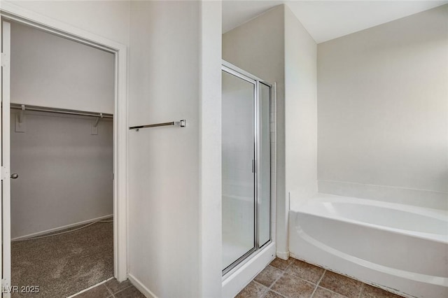 bathroom featuring a shower stall, a walk in closet, and a bath