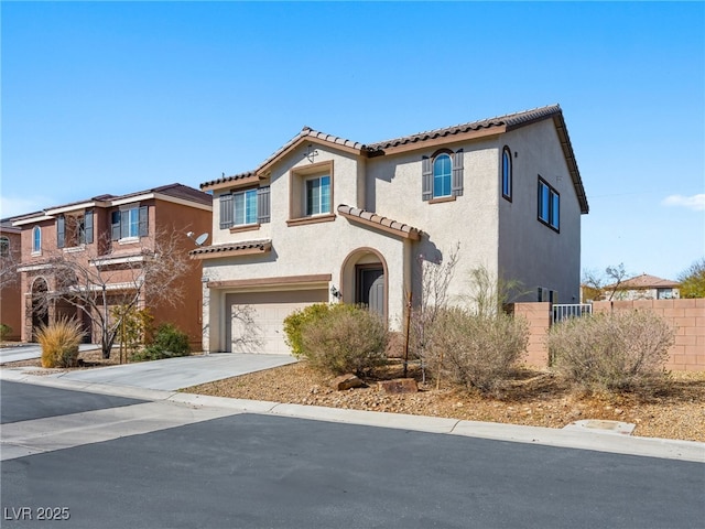 mediterranean / spanish home with a garage, concrete driveway, fence, and stucco siding