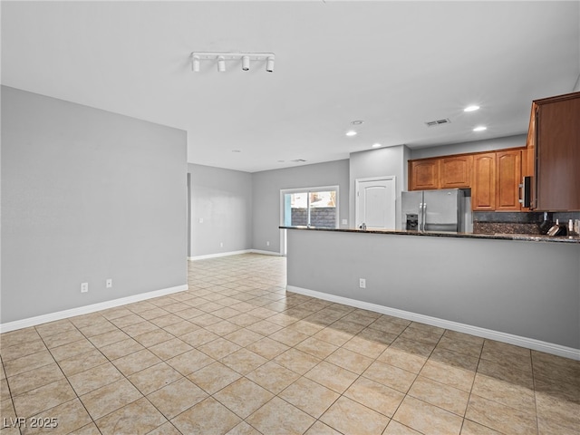 kitchen featuring visible vents, baseboards, open floor plan, stainless steel fridge with ice dispenser, and brown cabinetry