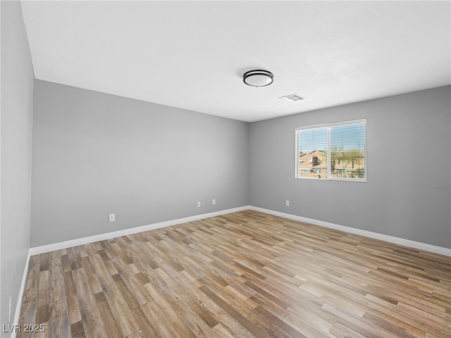 empty room featuring baseboards, visible vents, and light wood finished floors