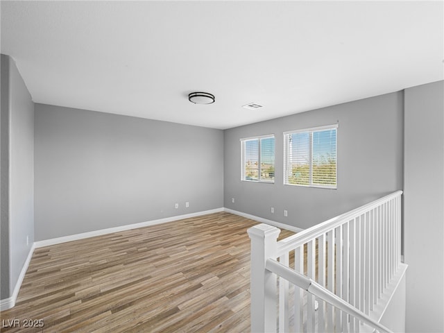 empty room with light wood-style floors, visible vents, and baseboards