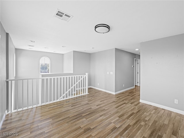 unfurnished room featuring baseboards, visible vents, and wood finished floors