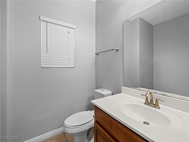 half bath with toilet, tile patterned flooring, baseboards, and vanity