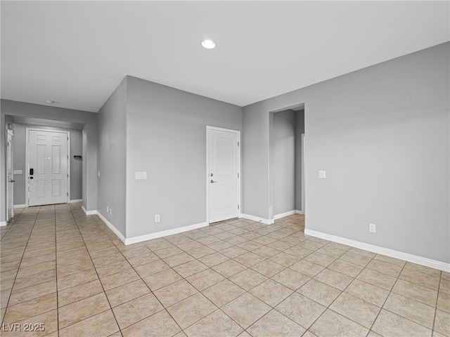 empty room with light tile patterned flooring and baseboards