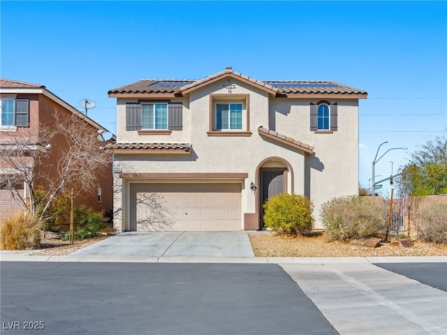 mediterranean / spanish-style home with a garage, stucco siding, a tile roof, and roof mounted solar panels