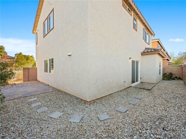 back of house featuring a tiled roof, a patio area, a fenced backyard, and stucco siding