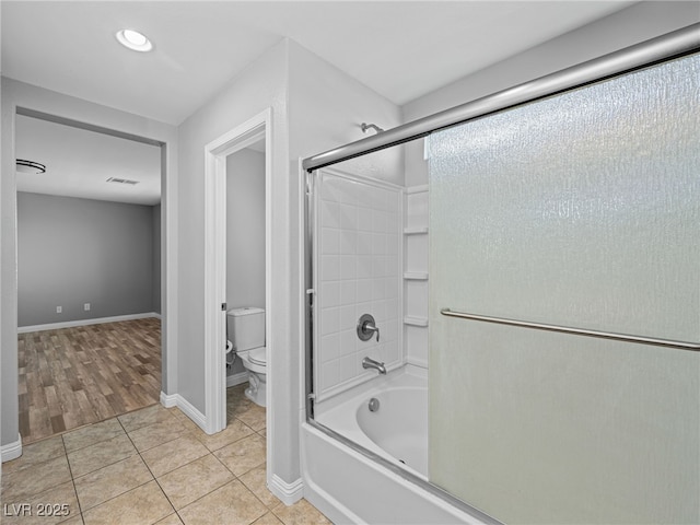 bathroom with toilet, visible vents, baseboards, combined bath / shower with glass door, and tile patterned floors