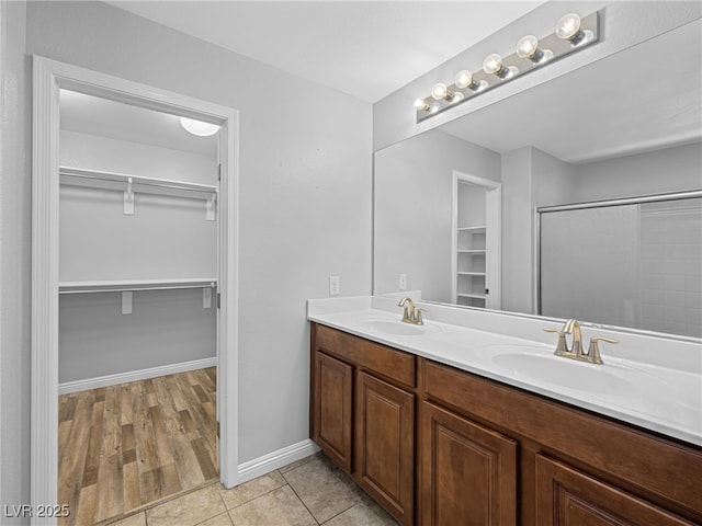 bathroom featuring tile patterned flooring, a sink, a spacious closet, and double vanity