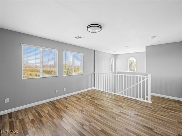 empty room featuring baseboards, visible vents, and wood finished floors