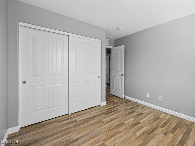 unfurnished bedroom with a closet, baseboards, and wood finished floors