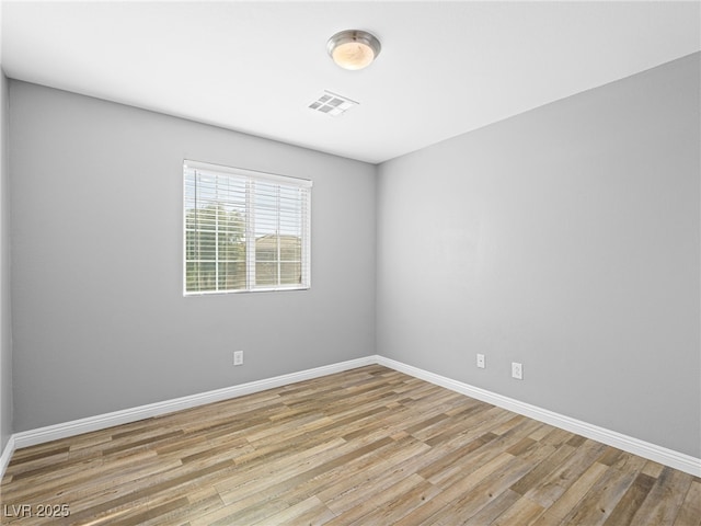 empty room featuring light wood-style floors, visible vents, and baseboards