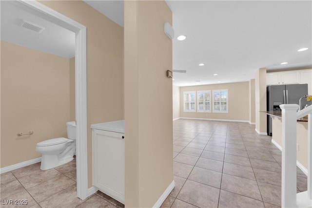 interior space featuring visible vents, baseboards, toilet, tile patterned floors, and recessed lighting