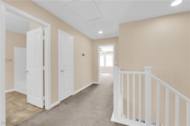 hall with attic access, baseboards, carpet flooring, and an upstairs landing