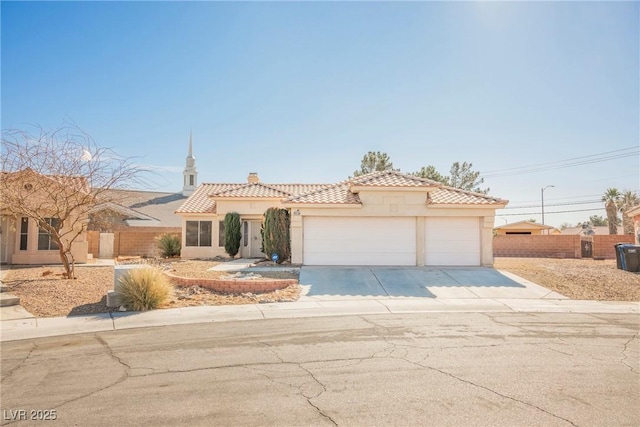 mediterranean / spanish house with stucco siding, concrete driveway, fence, a garage, and a tiled roof