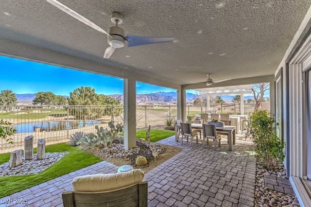 view of patio / terrace with ceiling fan, outdoor dining space, a fenced backyard, and a mountain view