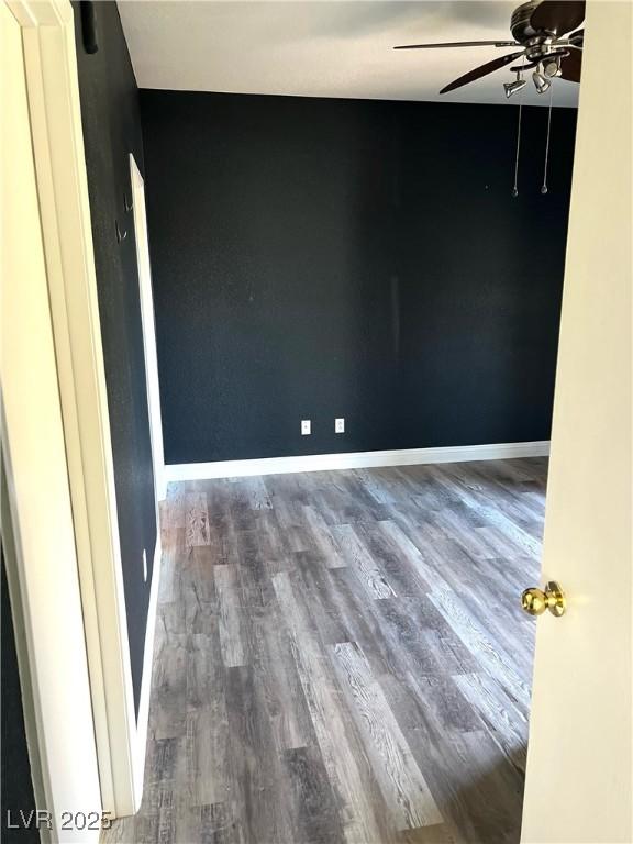 empty room featuring ceiling fan, baseboards, and wood finished floors