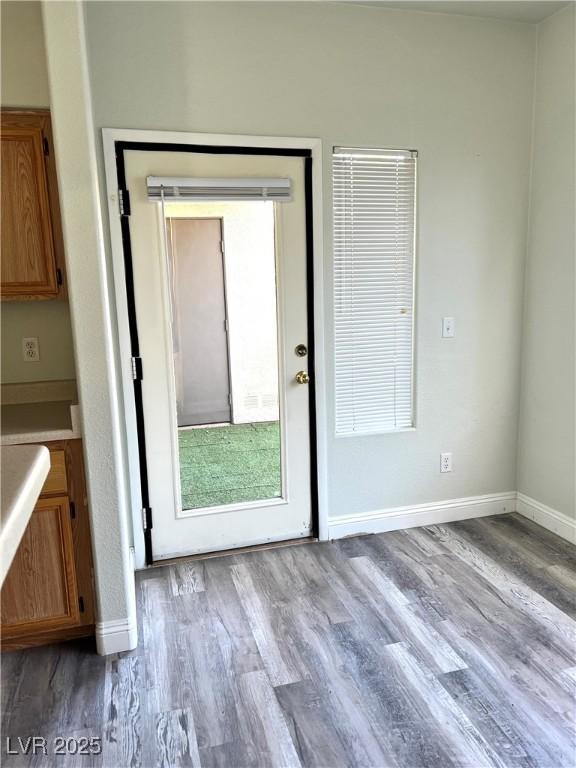 doorway to outside featuring baseboards and wood finished floors