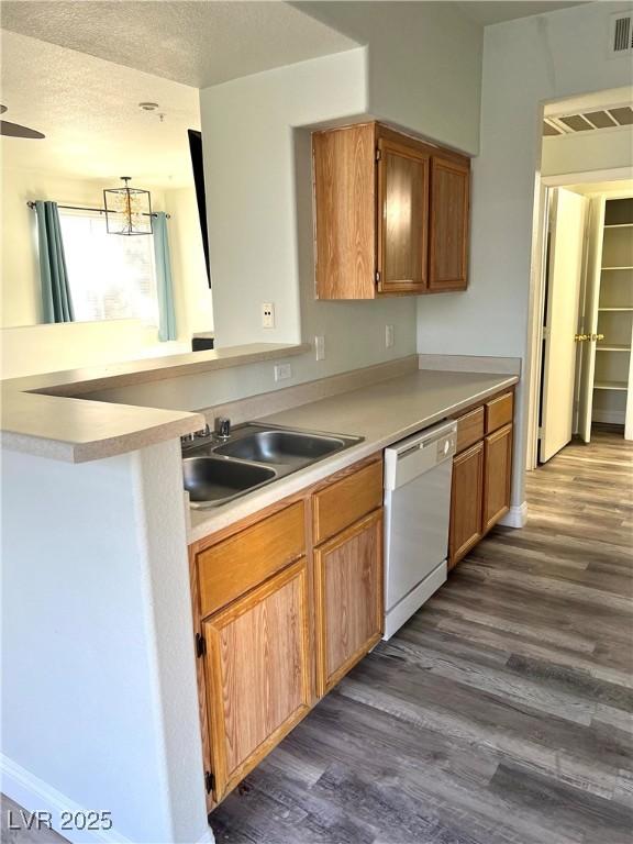 kitchen featuring a textured ceiling, dark wood finished floors, light countertops, and dishwasher