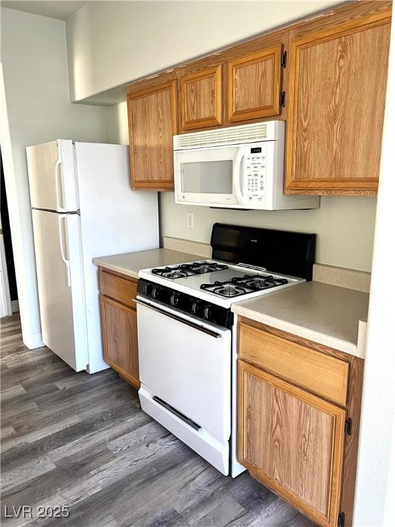 kitchen featuring light countertops, white appliances, dark wood finished floors, and brown cabinets