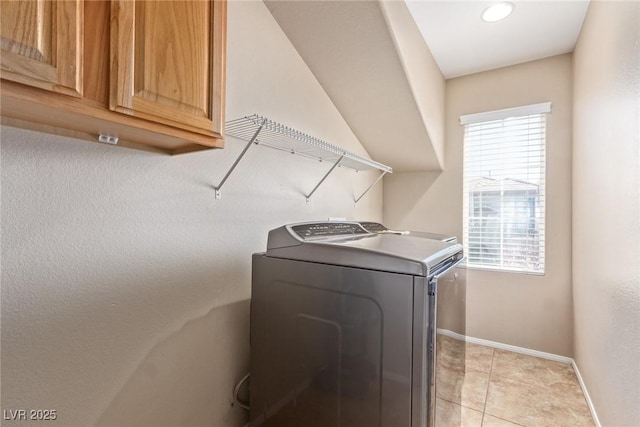 laundry area featuring cabinet space, baseboards, and light tile patterned floors