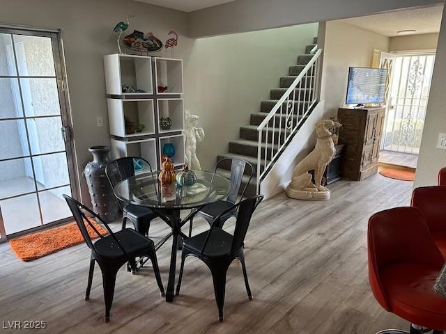 dining room with plenty of natural light, stairs, and wood finished floors