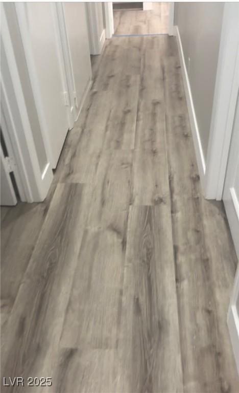 corridor with light wood-type flooring and baseboards