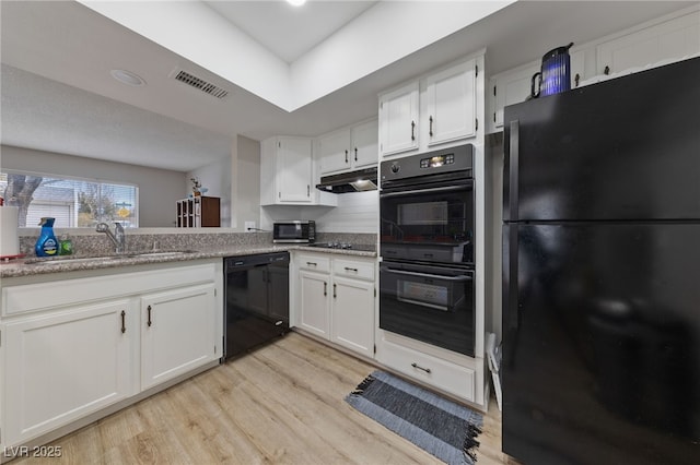 kitchen featuring light wood finished floors, visible vents, under cabinet range hood, white cabinets, and black appliances