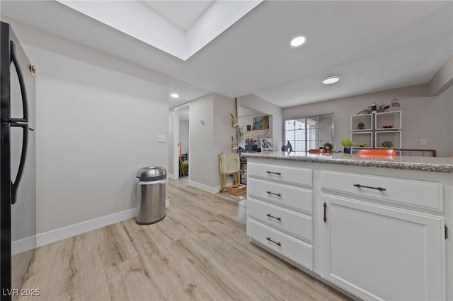kitchen with baseboards, light wood-style flooring, recessed lighting, freestanding refrigerator, and white cabinetry