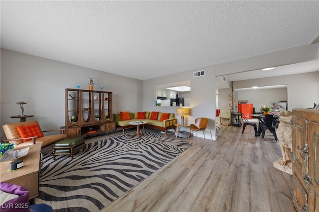 living room with wood finished floors, visible vents, and a textured ceiling