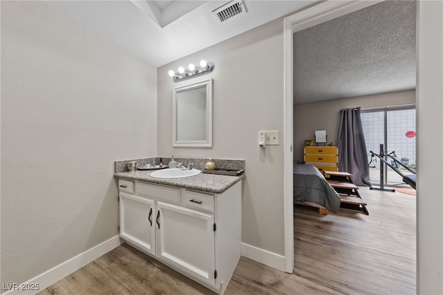 bathroom with visible vents, vanity, baseboards, and wood finished floors