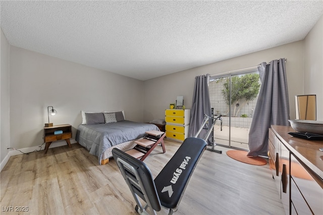bedroom with access to exterior, light wood finished floors, and a textured ceiling