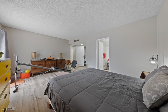 bedroom featuring visible vents, a textured ceiling, and wood finished floors