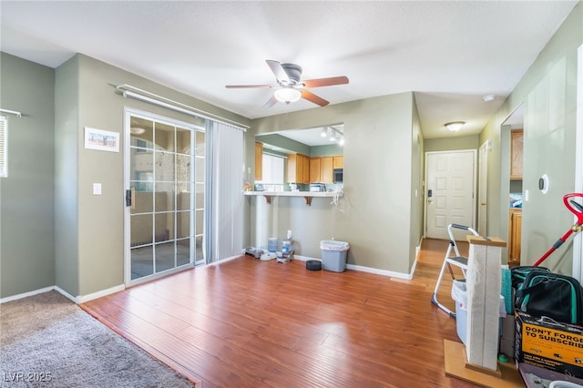 living room featuring light wood-style flooring, baseboards, and a ceiling fan